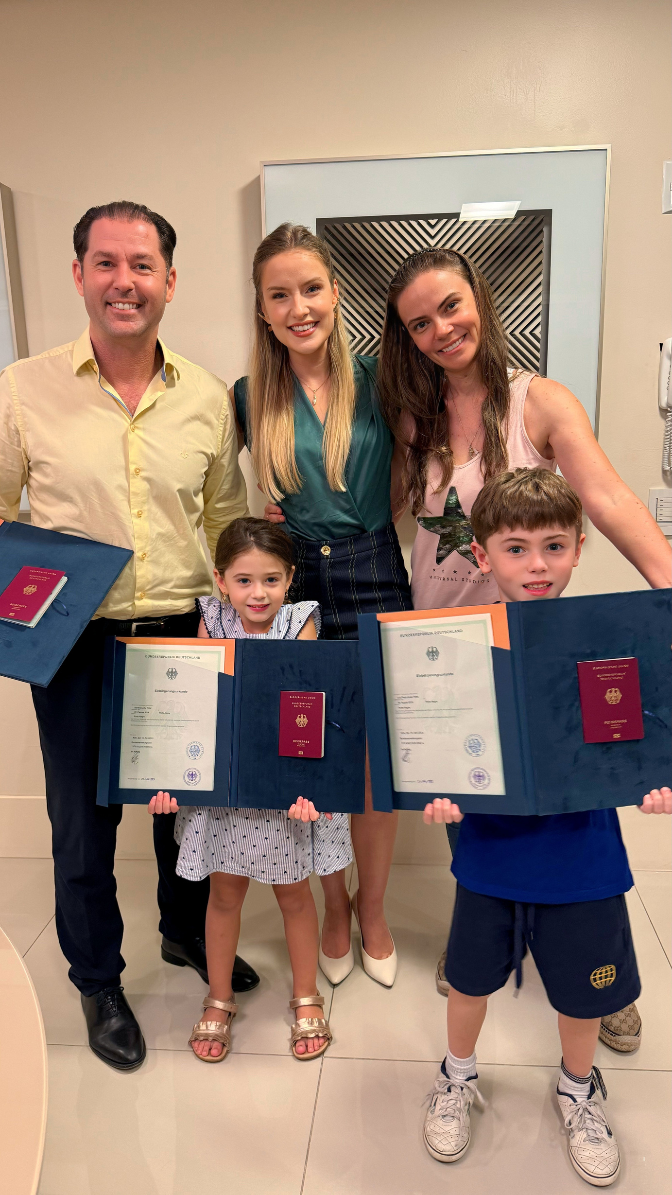 Família com crianças segurando pastas Europass com certificados e passaportes alemães